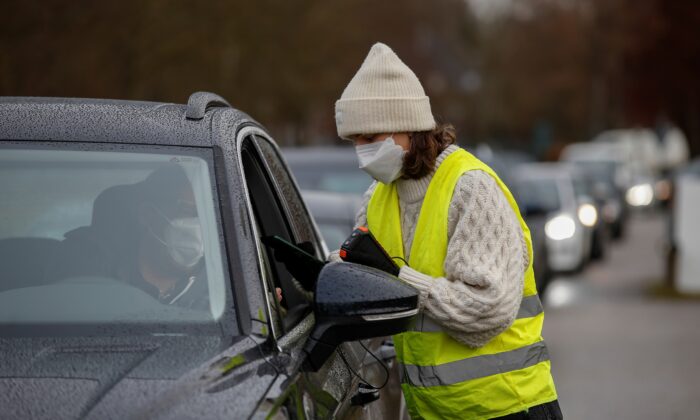A woman takes the digital data of a man at a drive through rapid coronavirus disease (COVID-19) test centre amid the COVID-19 pandemic in Furstenfeldbruck, Germany, on Nov. 27, 2021. (Michaela Rehle/Reuters)