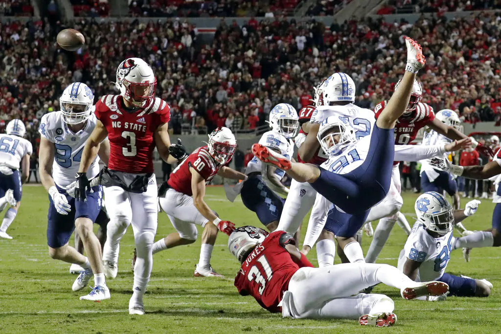 North Carolina punter Ben Kiernan (91) is upended after North Carolina State linebacker Vi Jones (31) blocked his punt during the first half of an NCAA college football game in Raleigh, N.C., on Nov. 26, 2021. (Chris Seward/AP Photo)