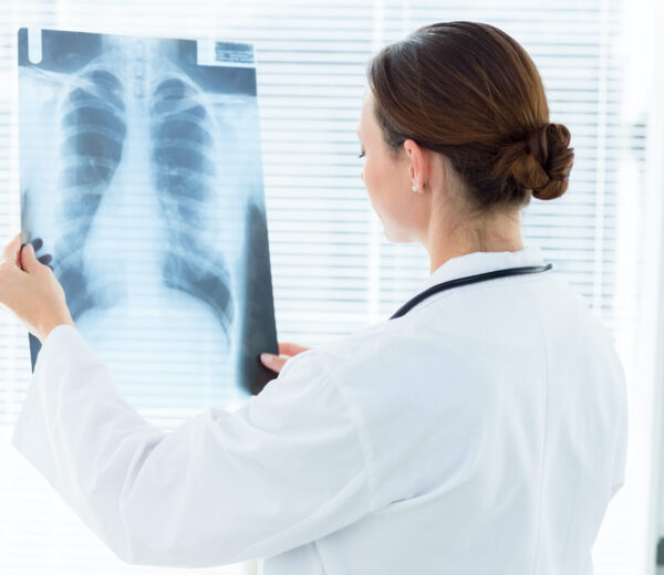 Rear,View,Of,Female,Doctor,Analyzing,Xray,Report,In,Clinic