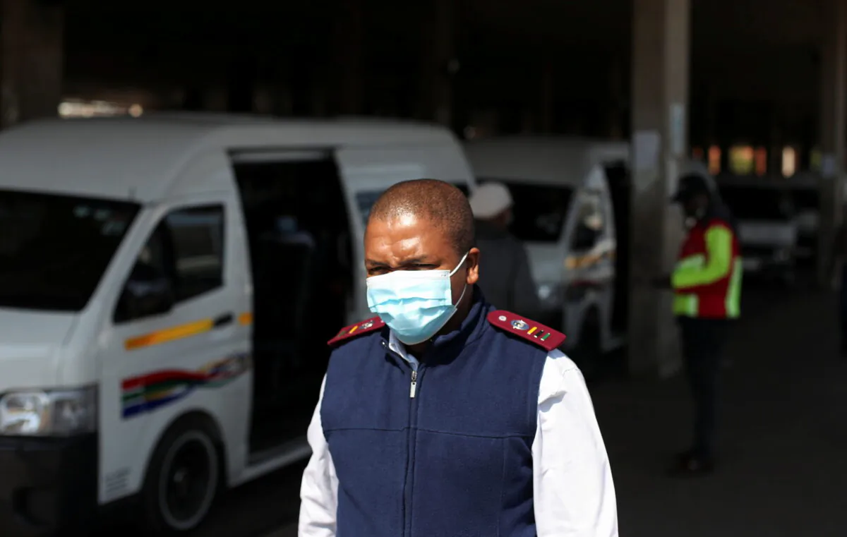 A health worker walks past a taxi after the announcement of a British ban on flights from South Africa, in Soweto, South Africa on Nov. 26, 2021. (Siphiwe Sibeko/Reuters)