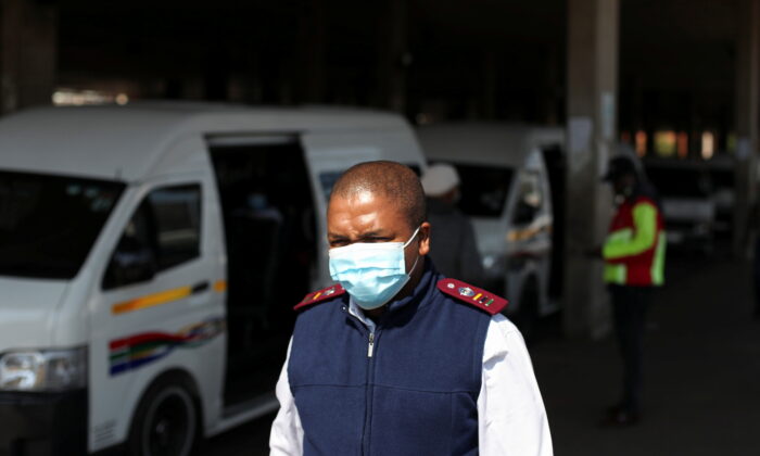 A health worker walks past a taxi after the announcement of a British ban on flights from South Africa, in Soweto, South Africa on Nov. 26, 2021. (Siphiwe Sibeko/Reuters)