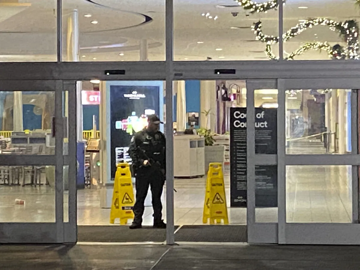 An officer guards an entrance to the Tacoma Mall in Tacoma, Wash., late on Nov. 26, 2021. (Craig Sailor/The News Tribune via AP)
