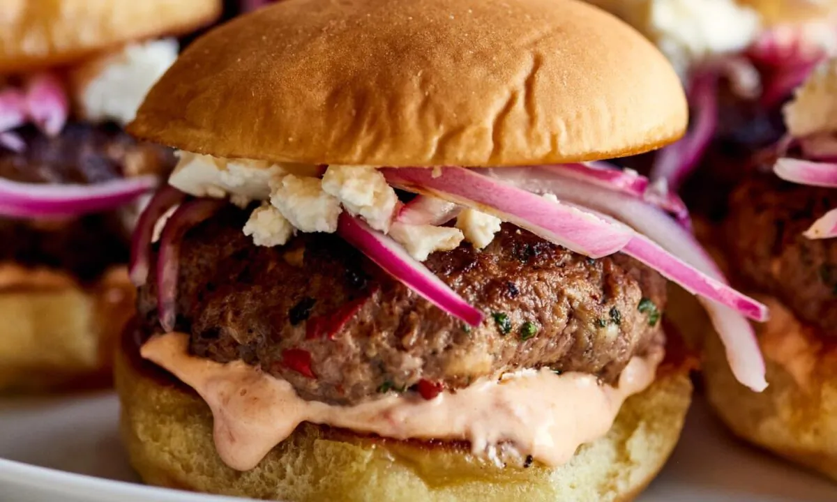 Harissa and lamb make for a dynamic duo in these sliders topped with feta cheese, pickled onions, and harissa mayo. (Joe Lingeman/TNS)