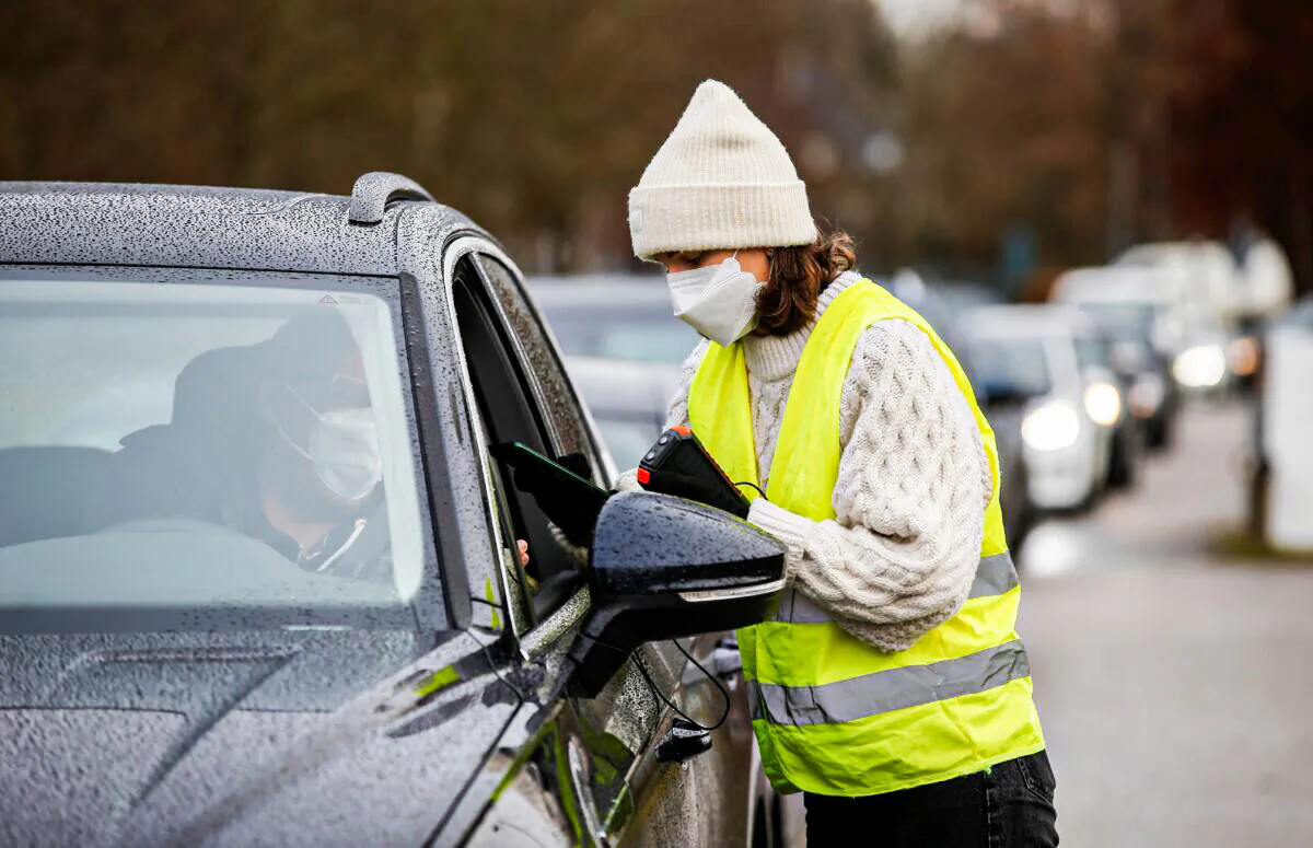 A woman takes the digital data of a man at a drive through rapid coronavirus disease (COVID-19) test centre amid the COVID-19 pandemic in Furstenfeldbruck, Germany, on Nov. 27, 2021. (Michaela Rehle/Reuters)