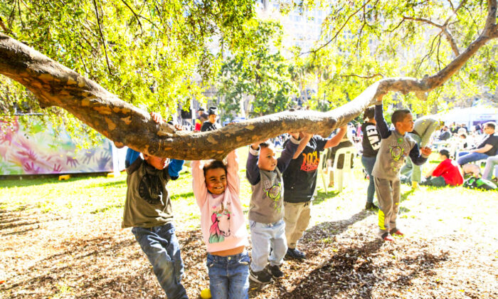 Children play on the branch of a tree at Hyde Park in Sydney, Australia, on July 13, 2019. (Jenny Evans/Getty Images)