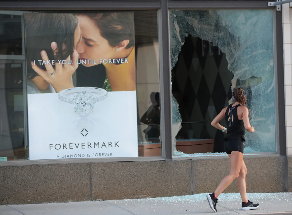 A file image of a jogger running past a broken storefront window after parts of the city had widespread looting and vandalism in Chicago, Ill., on Aug. 10, 2020. (Scott Olson/Getty Images)