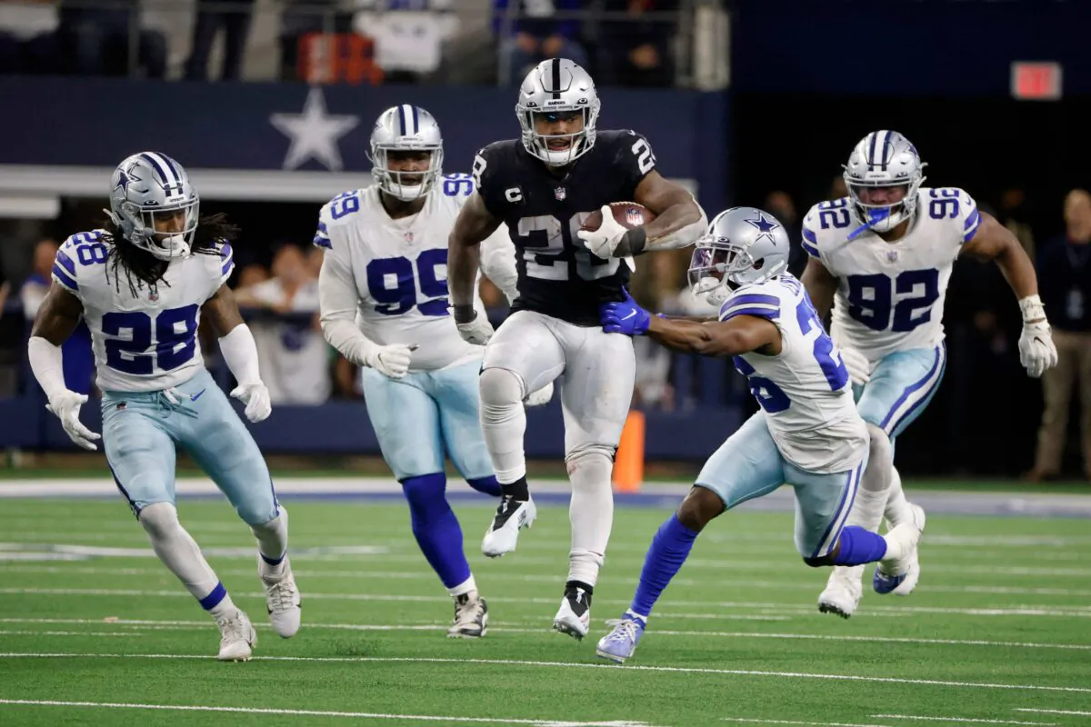 Las Vegas Raiders running back Josh Jacobs (28) runs the ball for a first down as Dallas Cowboys' Malik Hooker (28), Justin Hamilton (99), Jourdan Lewis (26) and Dorance Armstrong (92) attempt to make the stop in overtime of an NFL football game in Arlington, Texas, on Nov. 25, 2021. (Michael Ainsworth/AP Photo)