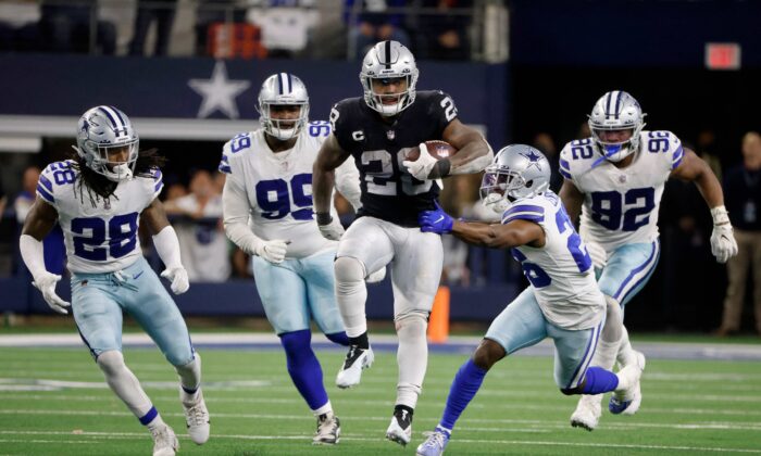 Las Vegas Raiders running back Josh Jacobs (28) runs the ball for a first down as Dallas Cowboys' Malik Hooker (28), Justin Hamilton (99), Jourdan Lewis (26) and Dorance Armstrong (92) attempt to make the stop in overtime of an NFL football game in Arlington, Texas, on Nov. 25, 2021. (Michael Ainsworth/AP Photo)
