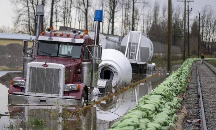 A truck gets swallowed up by rising flood waters from the United States as waters cross the border into Abbotsford, B.C., Nov. 29, 2021. (The Canadian Press/Jonathan Hayward)