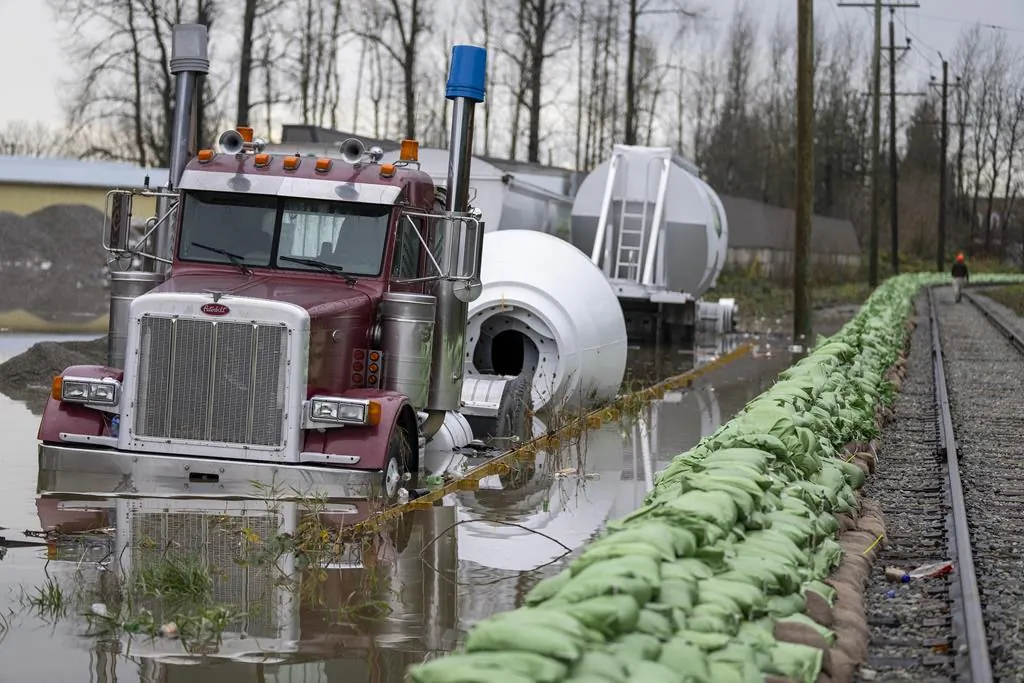 A truck gets swallowed up by rising flood waters from the United States as waters cross the border into Abbotsford, B.C., Nov. 29, 2021. (The Canadian Press/Jonathan Hayward)