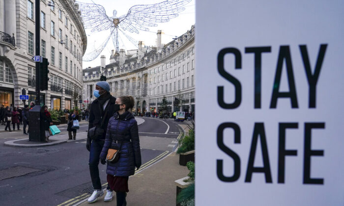 People wear face masks as they walk, in Regent Street, in London, Sunday, Nov. 28, 2021. (AP Photo/Alberto Pezzali)