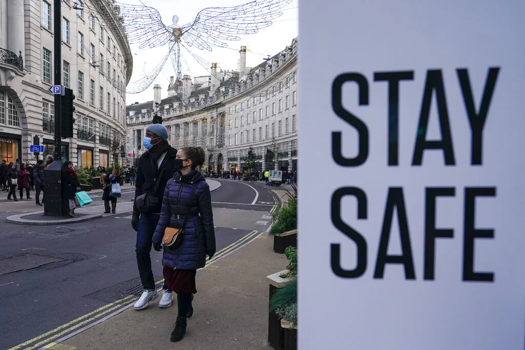 People wear face masks as they walk, in Regent Street, in London, Sunday, Nov. 28, 2021. (AP Photo/Alberto Pezzali)