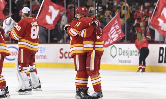 Calgary Flames defenseman Oliver Kylington (58) and forward Mikael Backlund (11) celebrate beating the Pittsburgh Penguins at Scotiabank Saddledome in Calgary, Alberta, Canada, on Nov 29, 2021. (Candice Ward/USA TODAY Sports via Field Level Media)