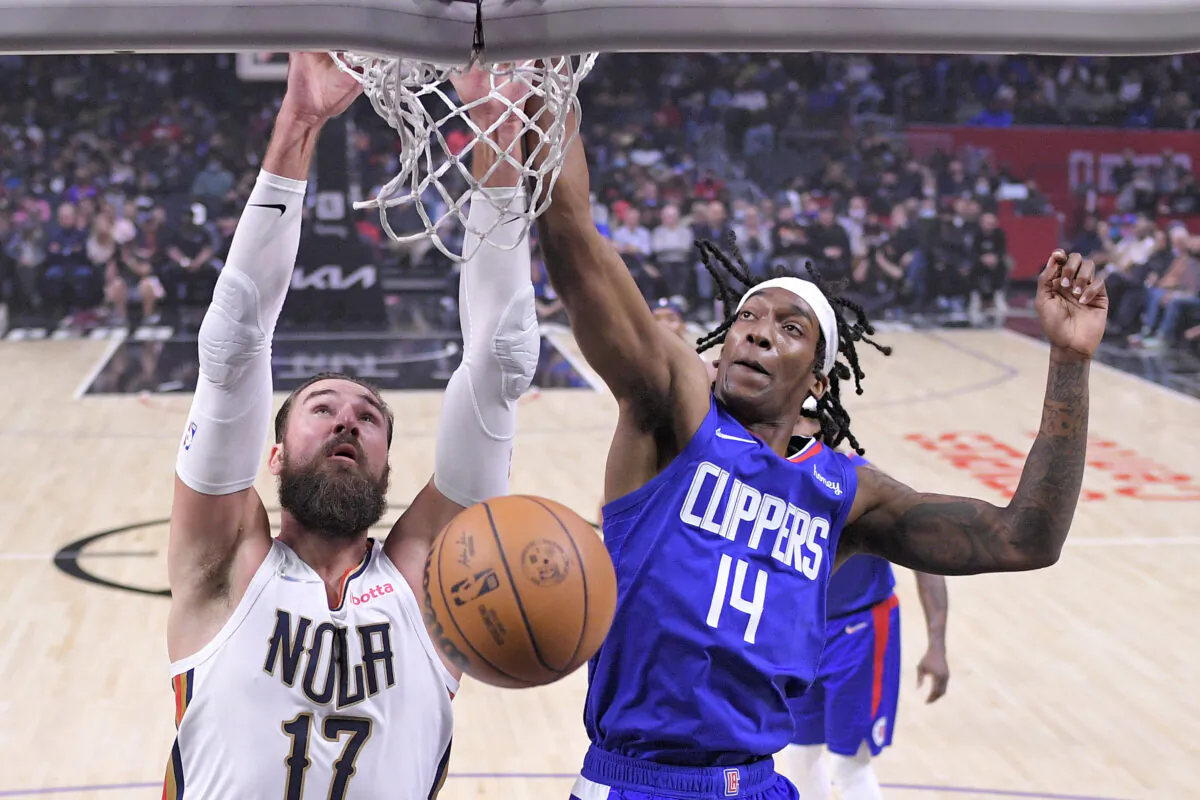 New Orleans Pelicans center Jonas Valanciunas, left, dunks as Los Angeles Clippers guard Terance Mann defends during the first half of an NBA basketball game in Los Angeles on Nov. 29, 2021. (AP Photo/Mark J. Terrill)
