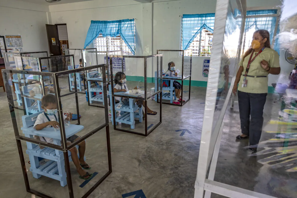 Elementary students sit inside dividers as a preventive measure against COVID-19 while attending in-person classes at Longos Elementary School in Alaminos in Pangasinan, Philippines, on Nov. 15, 2021. (Ezra Acayan/Getty Images)