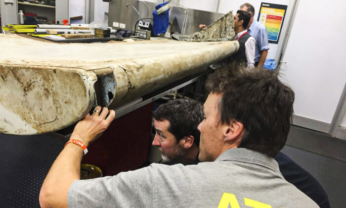 Staff from the Australian Transport Safety Bureau examine a piece of aircraft debris that is highly likely to have come from flight MH370 at their laboratory in Canberra, Australia, on July 20, 2016. (ATSB via AP, File)