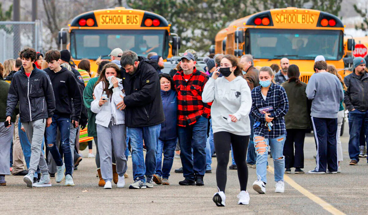 Parents walk away with their children from the Meijer's parking lot where many students gathered following an active shooter situation at Oxford High School in Oxford, Mich., on Nov. 30, 2021. (Eric Seals/USA TODAY NETWORK via Reuters)