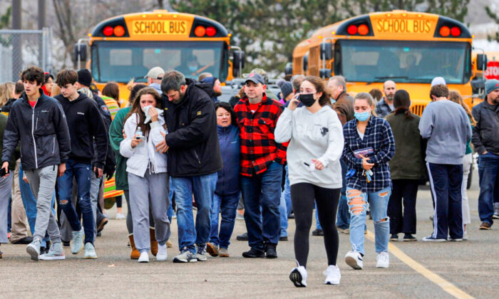 Parents walk away with their children from the Meijer's parking lot where many students gathered following an active shooter situation at Oxford High School in Oxford, Mich., on Nov. 30, 2021.  (Eric Seals/USA TODAY NETWORK via Reuters)