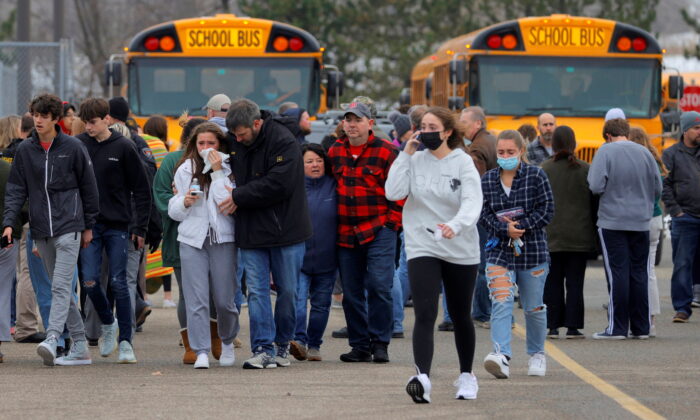 Parents walk away with their kids from the Meijer's parking lot where many students gathered following an active shooter situation at Oxford High School in Oxford, Mich., on Nov. 30, 2021. (Eric Seals/USA Today Network via Reuters)