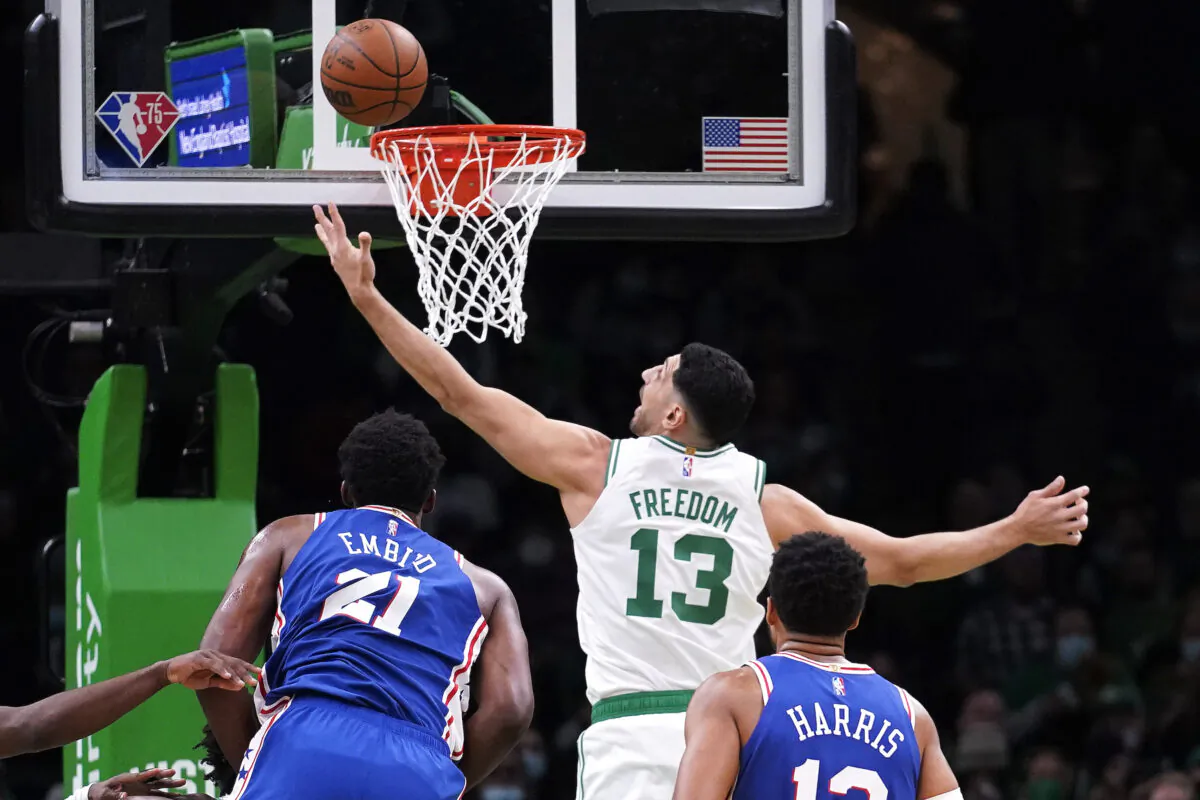 Boston Celtics center Enes Kanter Freedom (13) reaches for a rebound against Philadelphia 76ers center Joel Embiid (21) during the first half of an NBA basketball game. The Boston Celtics center changed his name from Enes Kanter to Enes Kanter Freedom in celebration of him officially becoming a United States citizen on Monday. Game was played in Boston, on Dec. 1, 2021. (Charles Krupa/AP Photo)