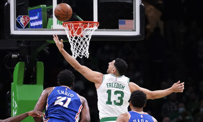 Boston Celtics center Enes Kanter Freedom (13) reaches for a rebound against Philadelphia 76ers center Joel Embiid (21) during the first half of an NBA basketball game. The Boston Celtics center changed his name from Enes Kanter to Enes Kanter Freedom in celebration of him officially becoming a United States citizen on Monday. Game was played in Boston, on Dec. 1, 2021. (Charles Krupa/AP Photo)