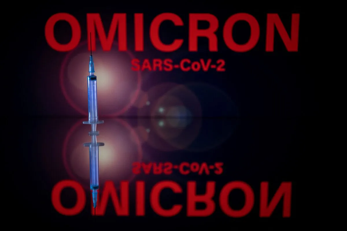 A syringe and a screen displaying Omicron, the name of the COVID-19 variant, on Dec. 1, 2021. (Lionel Bonaventure/AFP via Getty Images)