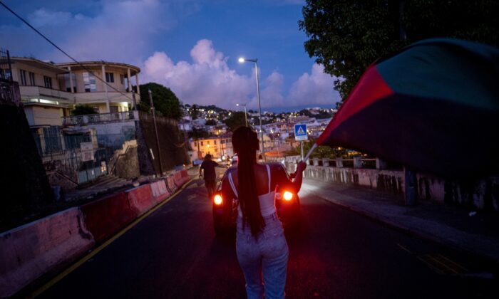 People participate in a peaceful protest against the government's coronavirus disease (COVID-19) protocols through downtown Fort de France after the unrest triggered by these curbs, which have already rocked the nearby island of Guadeloupe, in Fort-De-France, Martinique Nov. 28, 2021. (Ricardo Arduengo/Reuters)