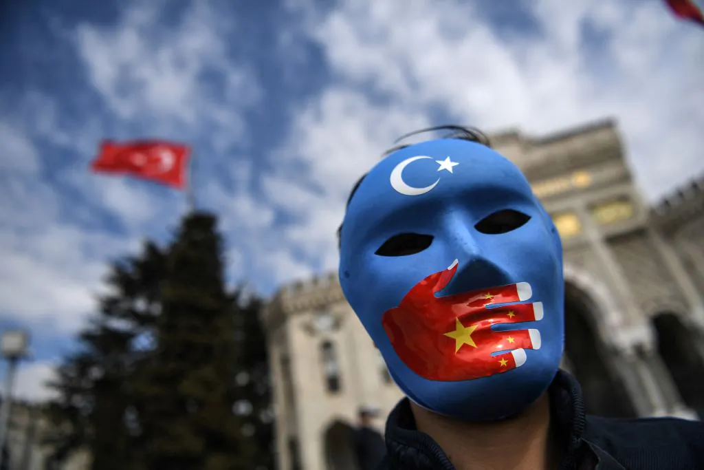 A demonstrator wearing a mask painted with the colors of the flag of East Turkestan takes part in a protest by supporters of the Uyghur minority on April 1, 2021, at Bayazit Square in Istanbul. (Ozan Kose/AFP via Getty Images)
