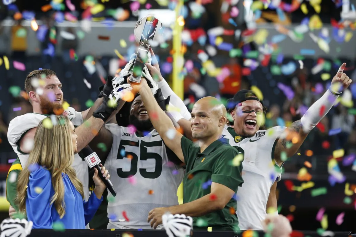 Baylor offensive lineman Connor Galvin, left, offensive lineman Xavier Newman-Johnson (55), head coach Dave Aranda, right, and linebacker Terrel Bernard, right, hold up the trophy as ABC commentator Molly McGrath, left, looks on after an NCAA college football game against Oklahoma State for the Big 12 Conference championship against Oklahoma State in Arlington, Texas, on Dec. 4, 2021. (Tim Heitman/AP Photo)