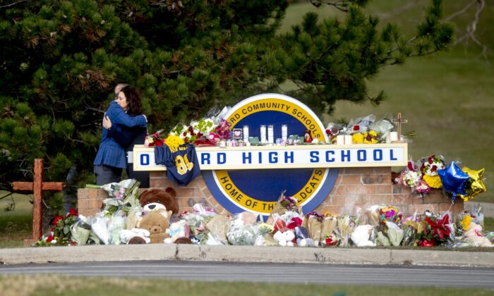 Gov. Gretchen Whitmer embraces Oakland County Executive Dave Coulter as the two leave flowers and pay their respects at Oxford High School in Oxford, Mich., on Dec. 2, 2021. (Jake May/ Flint Journal via AP)