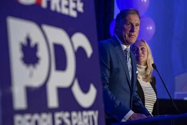 People's Party of Canada Leader Maxime Bernier and wife Catherine Letarte speaks from a podium to supporters during the PPC headquarters election night event in Saskatoon, Sask., Sept. 20, 2021. (The Canadian Press/Liam Richards)
