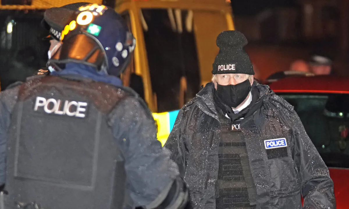 Prime Minister Boris Johnson (R) observes an early morning Merseyside Police raid on a home as part of 'Operation Toxic' to infiltrate county lines drug dealings, ahead of the publication of the government's 10-year drug strategy, in Liverpool, England, on Dec. 6, 2021. (Christopher Furlong/PA)