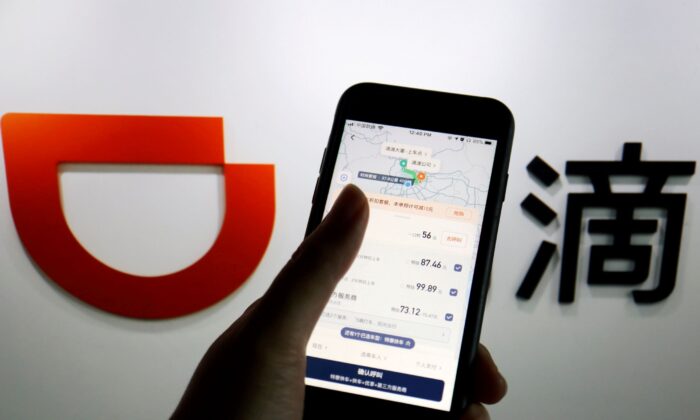 The app of Chinese ride-hailing giant Didi is seen on a mobile phone in front of the company logo, picture taken on July 1, 2021. (Florence Lo/Illustration/Reuters)