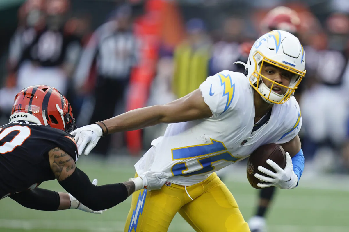 Los Angeles Chargers' Jalen Guyton (15) runs out of the tackle of Cincinnati Bengals' Jessie Bates (30) during the second half of an NFL football game in Cincinnati on Dec. 5, 2021. (Michael Conroy/AP Photo)