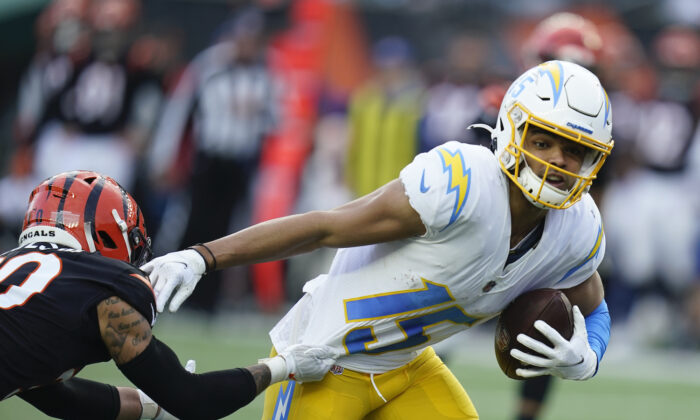 Los Angeles Chargers' Jalen Guyton (15) runs out of the tackle of Cincinnati Bengals' Jessie Bates (30) during the second half of an NFL football game in Cincinnati on Dec. 5, 2021. (Michael Conroy/AP Photo)