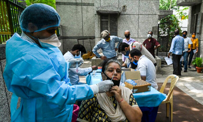 A health worker takes a swab sample from a woman for a reverse transcription polymerase chain reaction (RT-PCR) test for the Covid-19 coronavirus at a health centre in New Delhi, India, on June 10, 2021.  (Prakash Singh/AFP via Getty Images)