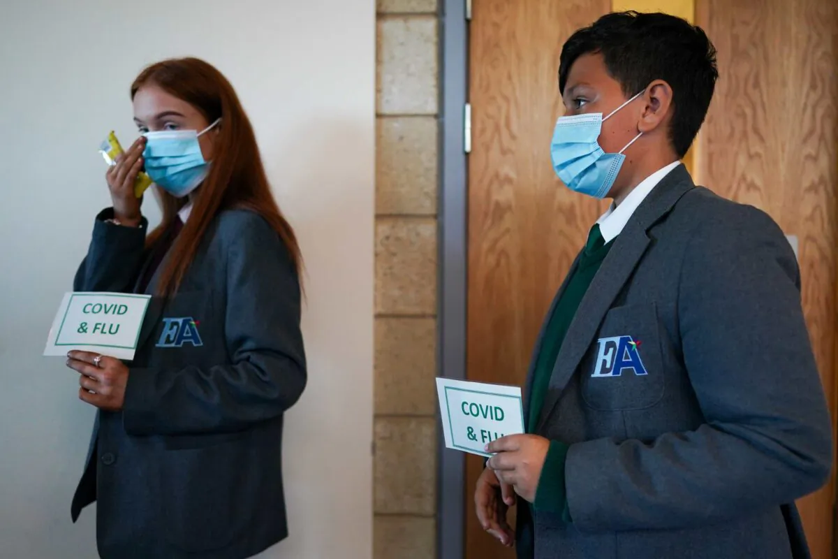Lauren McLean, 15, and Felix Dima, 13, attend a clinic to receive their flu and Pfizer-BioNTech COVID-19 vaccinations at the Excelsior Academy  in Newcastle upon Tyne, England, on Sept. 22, 2021. (Ian Forsyth/Getty Images)
