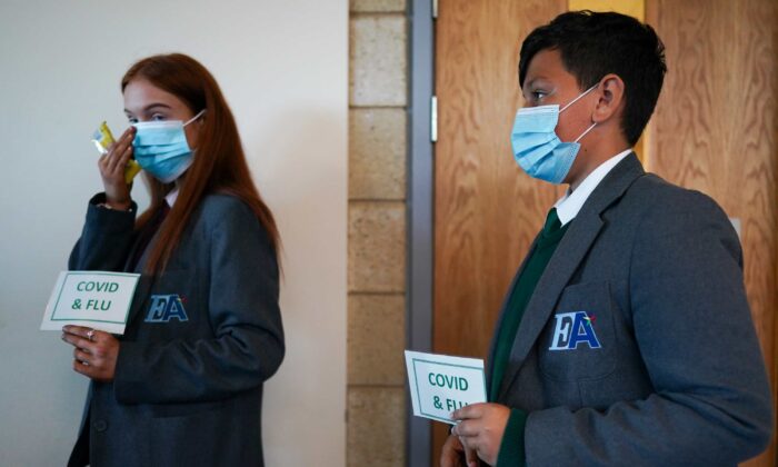 Lauren McLean, 15, and Felix Dima, 13, attend a clinic to receive their flu and Pfizer-BioNTech COVID-19 vaccinations at the Excelsior Academy  in Newcastle upon Tyne, England, on Sept. 22, 2021. (Ian Forsyth/Getty Images)