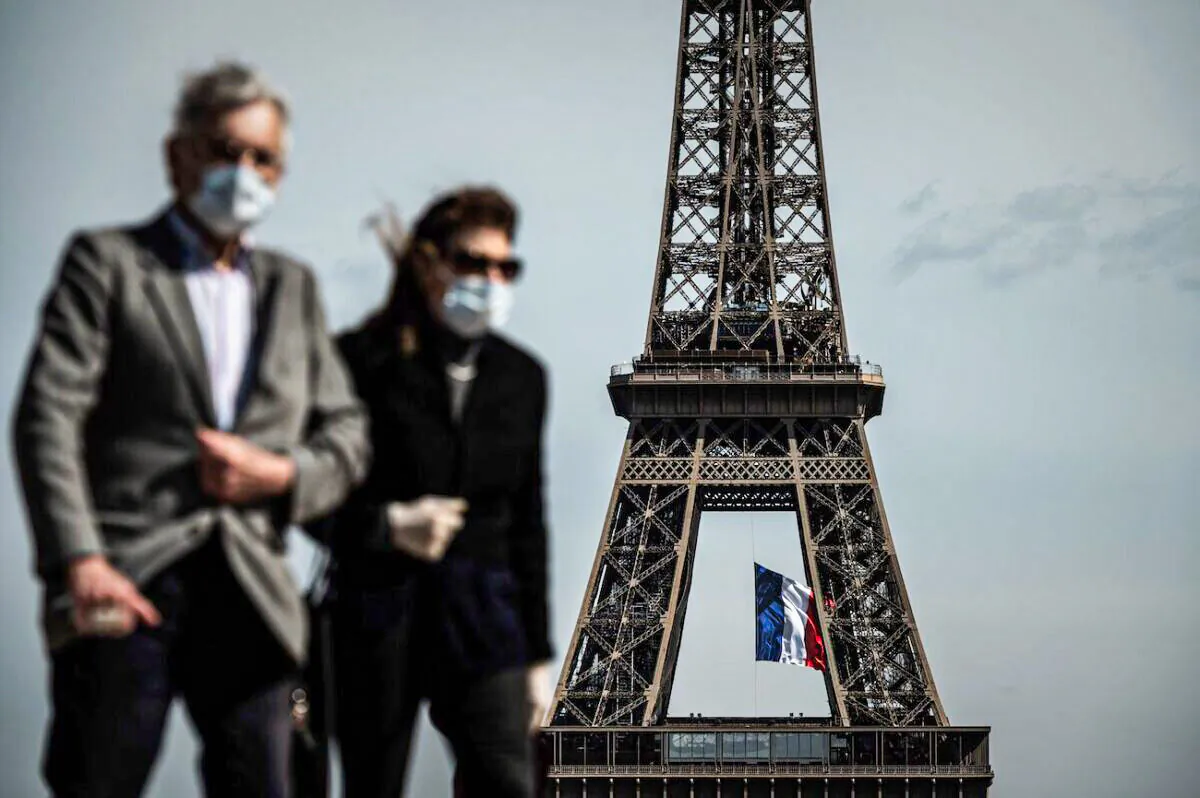 A man and a woman walk on Trocadero Plaza as a French national flag flies on the Eiffel Tower in background in Paris on May 11, 2020. (Philippe Lopez/AFP via Getty Images)