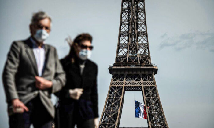 A man and a woman walk on Trocadero Plaza as a French national flag flies on the Eiffel Tower in background in Paris on May 11, 2020. (Philippe Lopez/AFP via Getty Images)