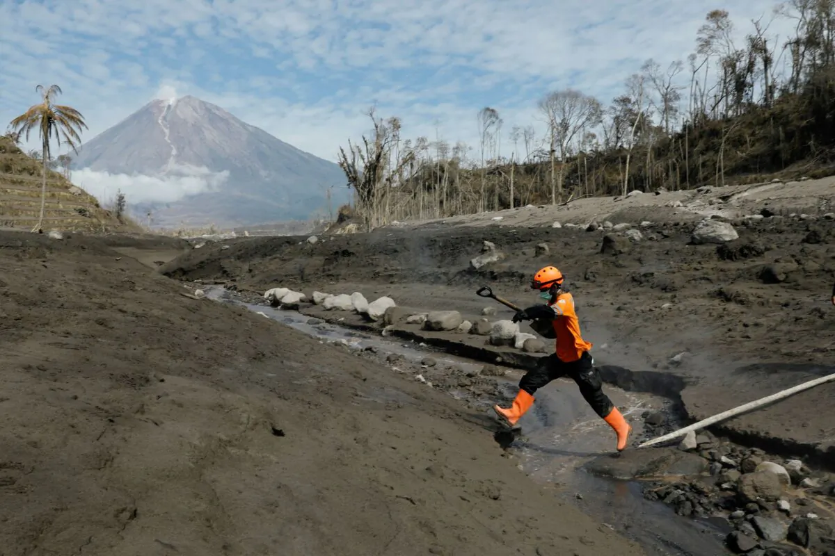 A rescue worked jumps across the lava flow path at an area affected by the eruption of Mount Semeru volcano, in Curah Kobokan, Pronojiwo district, Lumajang, East Java province, Indonesia, on Dec. 8, 2021. (Willy Kurniawan/Reuters)