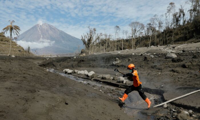 A rescue worked jumps across the lava flow path at an area affected by the eruption of Mount Semeru volcano, in Curah Kobokan, Pronojiwo district, Lumajang, East Java province, Indonesia, on Dec. 8, 2021. (Willy Kurniawan/Reuters)