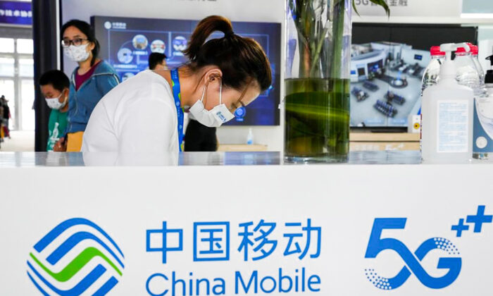 A worker wearing a mask waits for visitors to the China Mobile booth in Beijing, China, on Sept. 5, 2021. (Ng Han Guan/AP Photo)