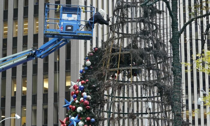 A worker disassembles a Christmas tree outside Fox News headquarters, in N.Y.C., on Dec. 8, 2021. (Richard Drew/AP Photo)