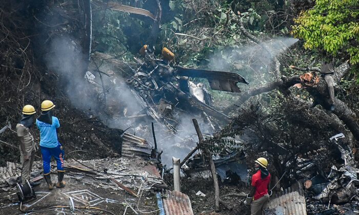Firemen and rescue workers stand next to the debris of an IAF Mi-17V5 helicopter crash site in Coonoor, Tamil Nadu, on Dec. 8, 2021. (AFP via Getty Images)
