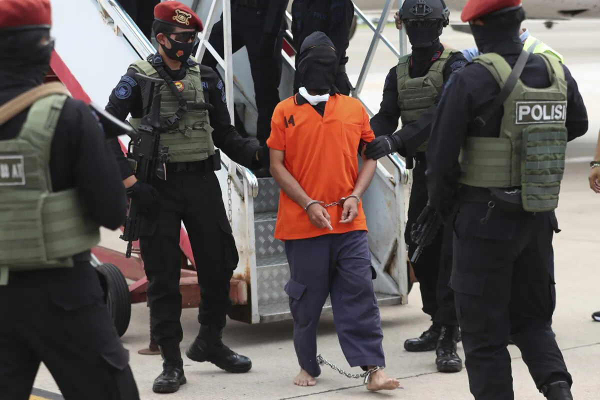 Police officers escort suspected Islamic terrorist Upik Lawanga (C) upon arrival following his arrest, at Soekarno-Hatta International Airport in Tangerang, Indonesia, on Dec. 16, 2020. (Achmad Ibrahim/AP Photo)
