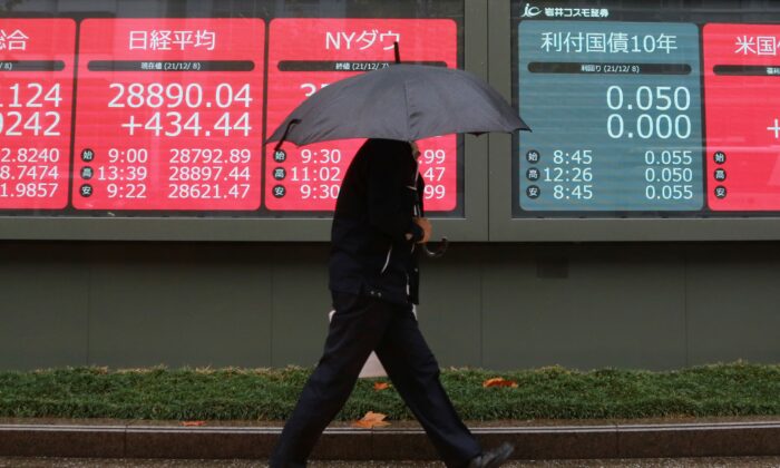 A man walks by an electronic stock board of a securities firm in Tokyo, Japan, on Dec. 8, 2021. (Koji Sasahara/AP Photo)