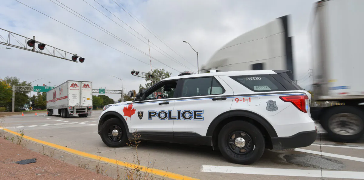 A police vehicle is on the scene as trucks make their way to the Ambassador Bridge border crossing in Windsor, Ont., on Oct.4, 2021. (The Canadian Press/Rob Gurdebeke)