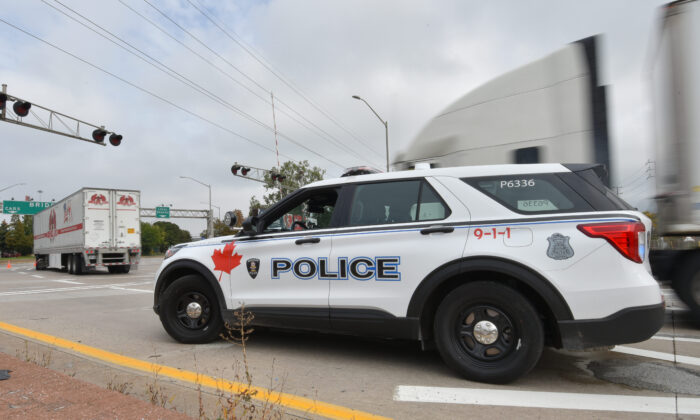 A police vehicle is on the scene as trucks make their way to the Ambassador Bridge border crossing in Windsor, Ont., on Oct.4, 2021. (The Canadian Press/Rob Gurdebeke)