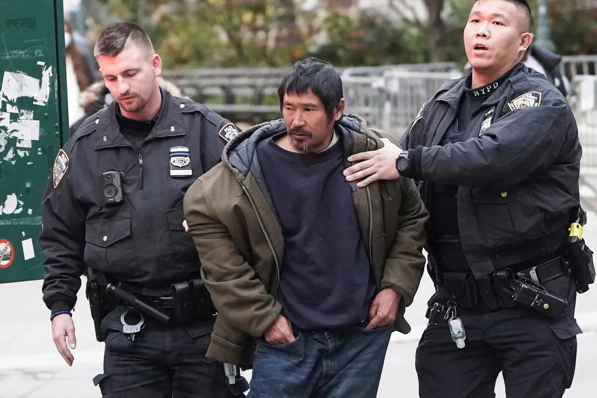Craig Tamanaha, who was later charged with setting fire to a Christmas tree outside the Fox News headquarters, is detained by police after exposing himself outside the court at the trial of Ghislaine Maxwell in the Manhattan borough of N.Y.C., on Nov. 29, 2021. (Carlo Allegri/Reuters)